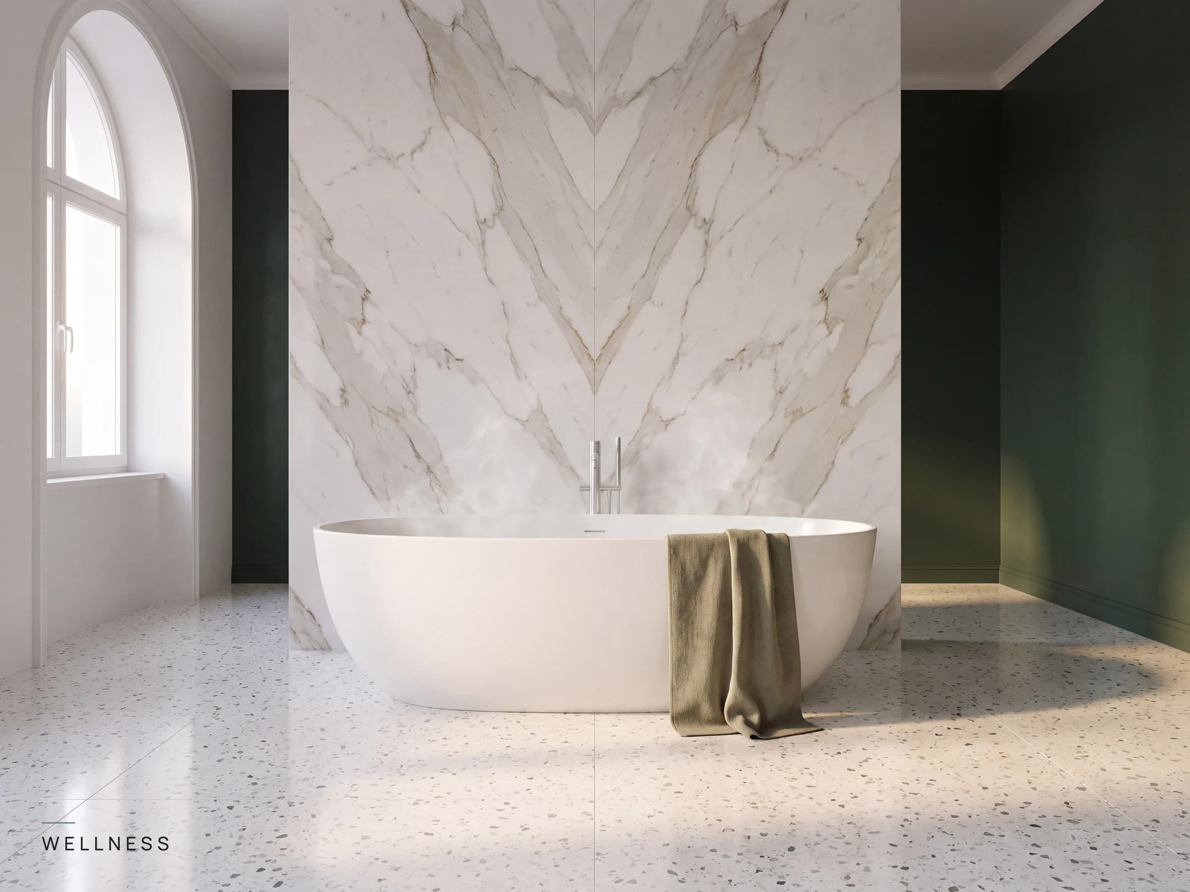 White freestanding oval bathtub against a book matched white marble wall with deep pine green walls, a dusty olive linen towel and warm evening light