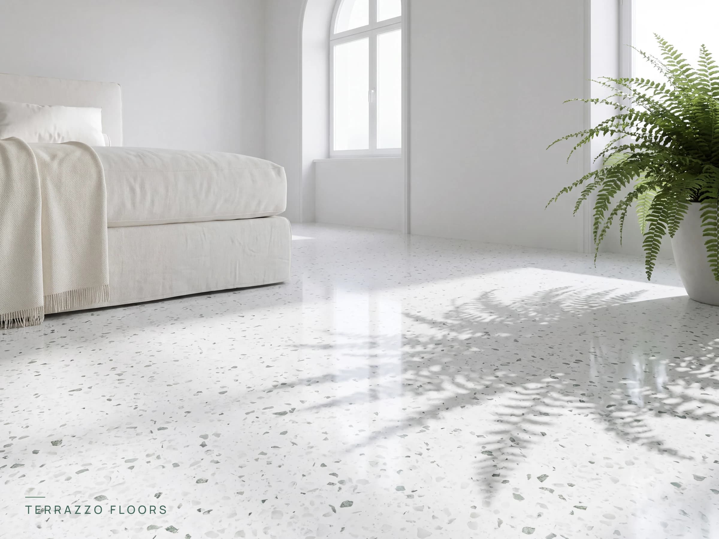 White-base terrazzo flooring with grey and green marble chips beside a linen daybed in bright daylight